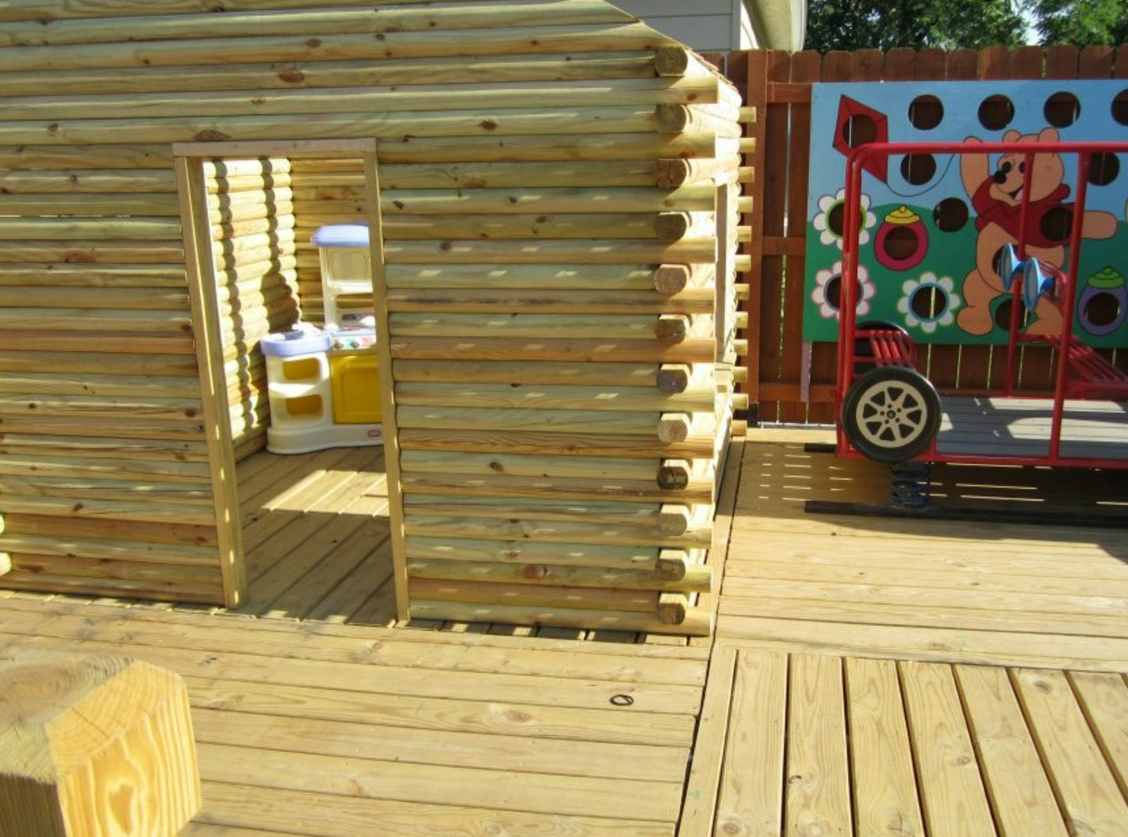 Wooden playhouse with a toy kitchen inside on a deck