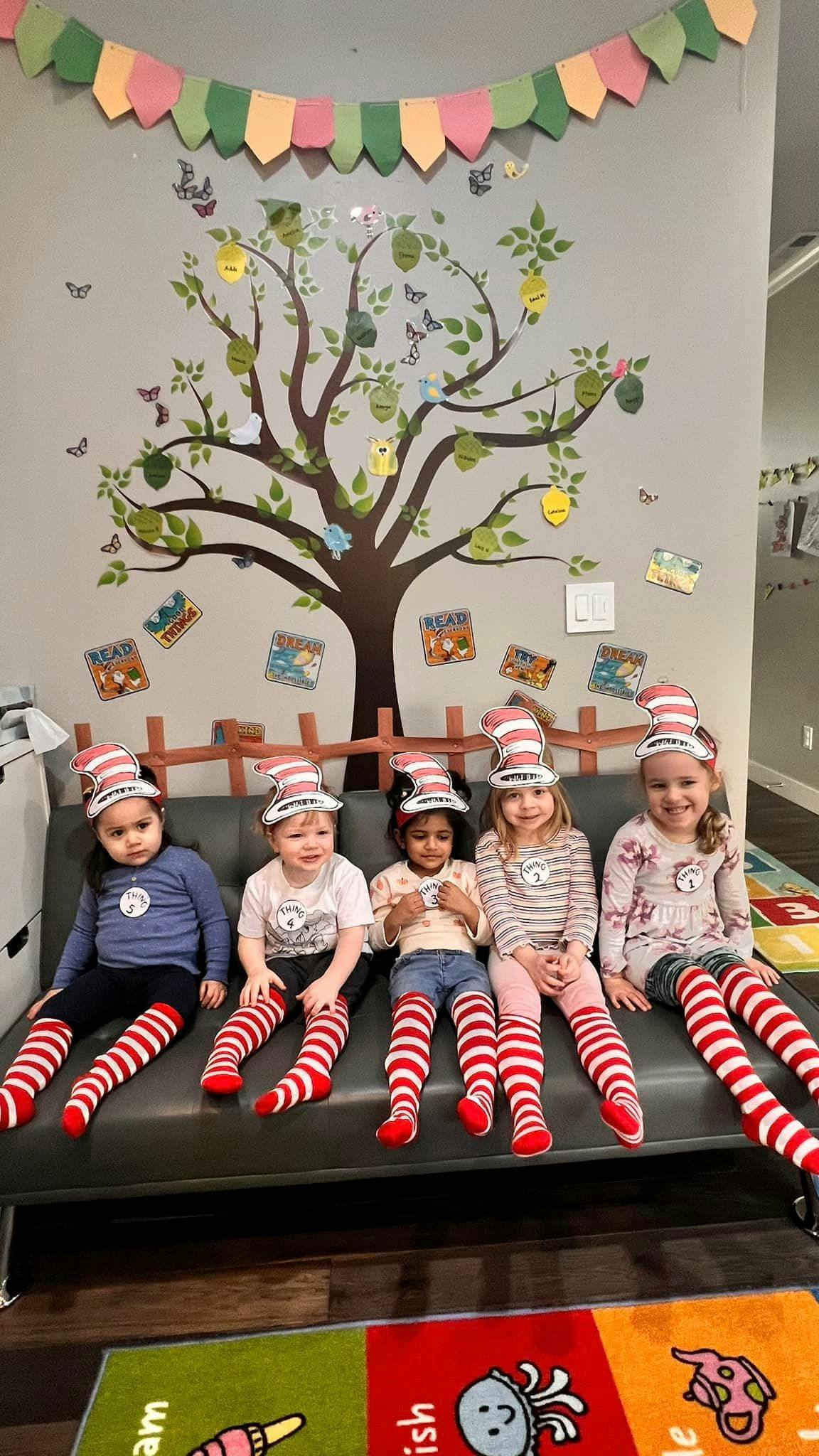 Five children wearing striped hats and socks sitting on a couch