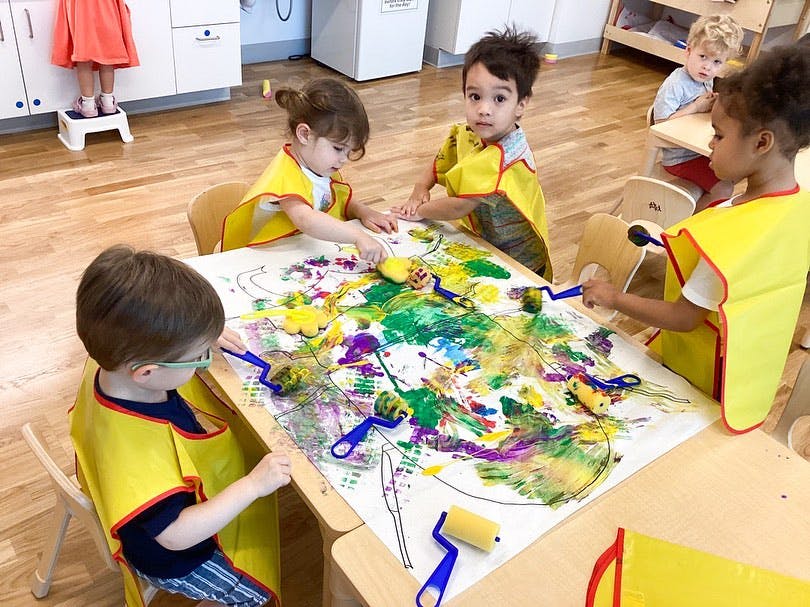 Children painting at a table in a classroom