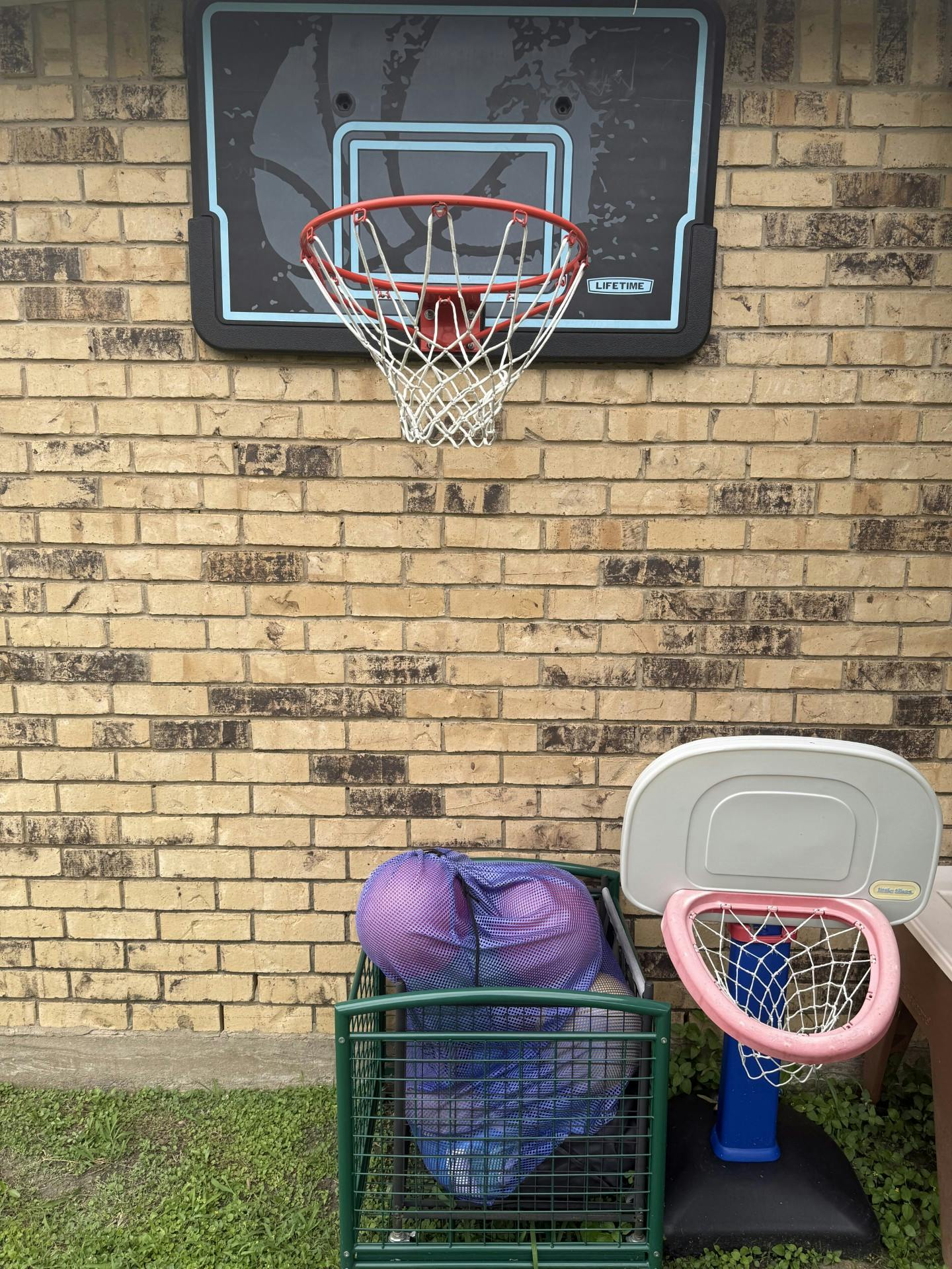 Basketball hoop on a brick wall, with a small pink basketball goal below