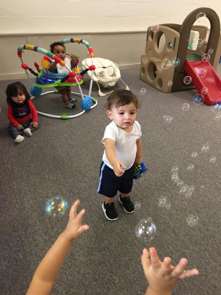 Three children playing with bubbles indoors