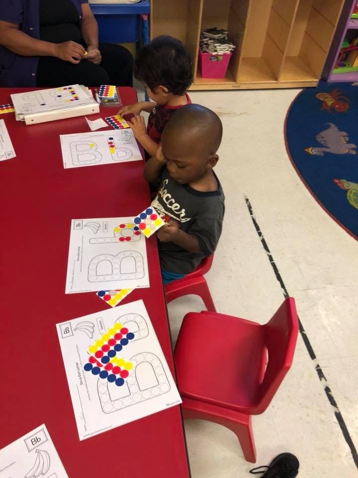 Two children at a table with papers and colorful stickers