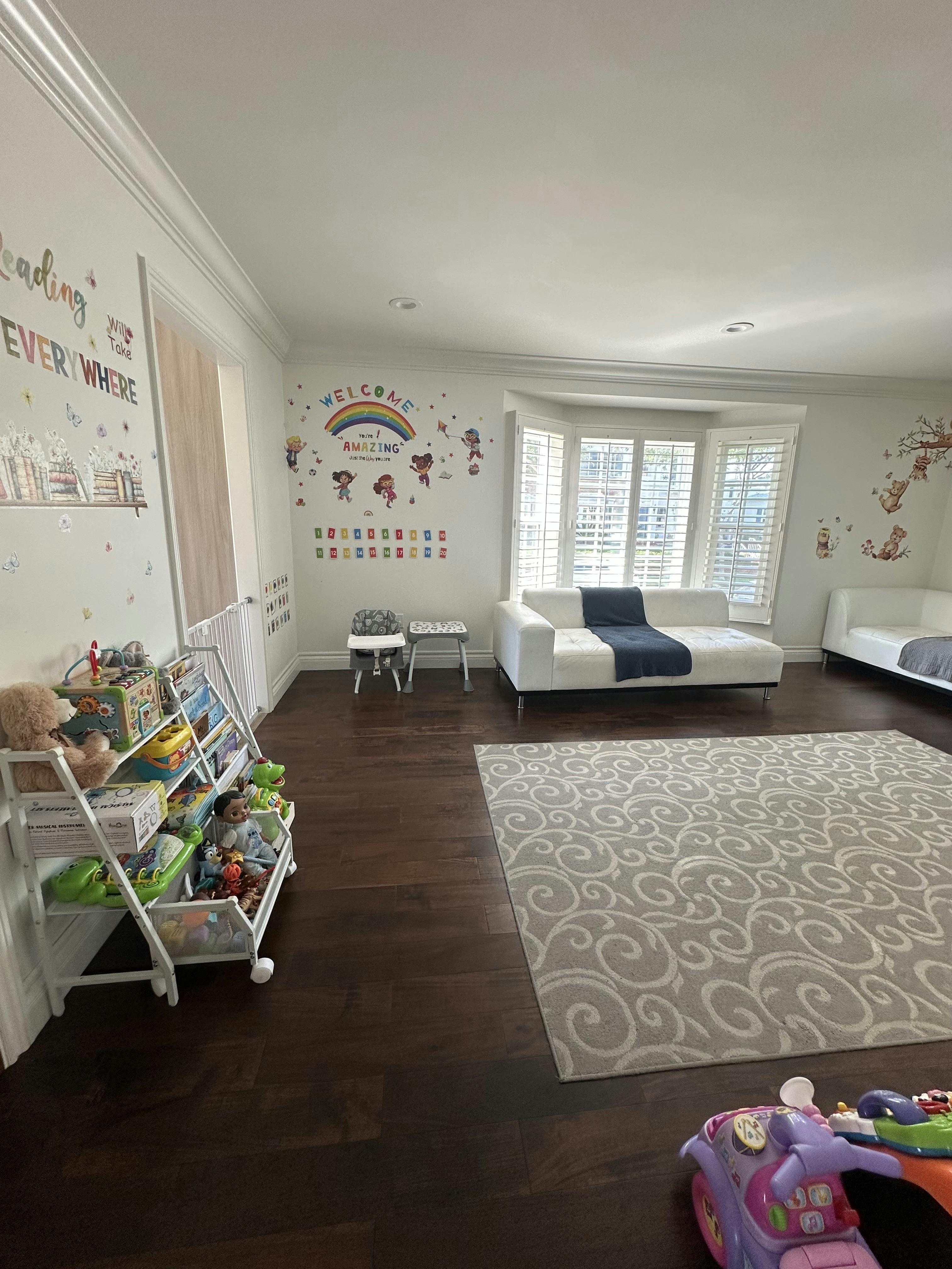 Playroom with children's toys, rug, and white sofas