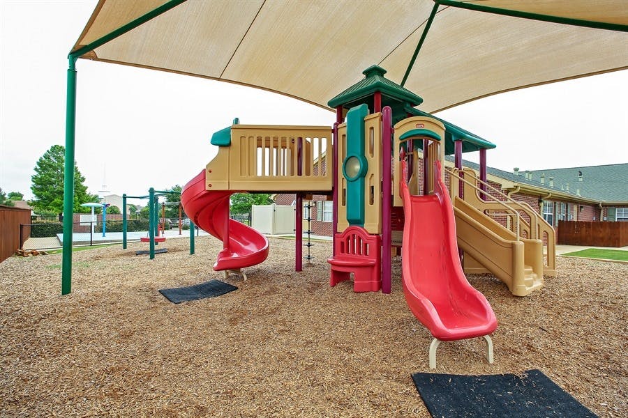 Playground with slides and climbing structures under a shade canopy