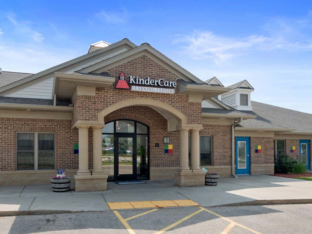 Brick building exterior with a "KinderCare Learning Centers" sign above the arched entrance