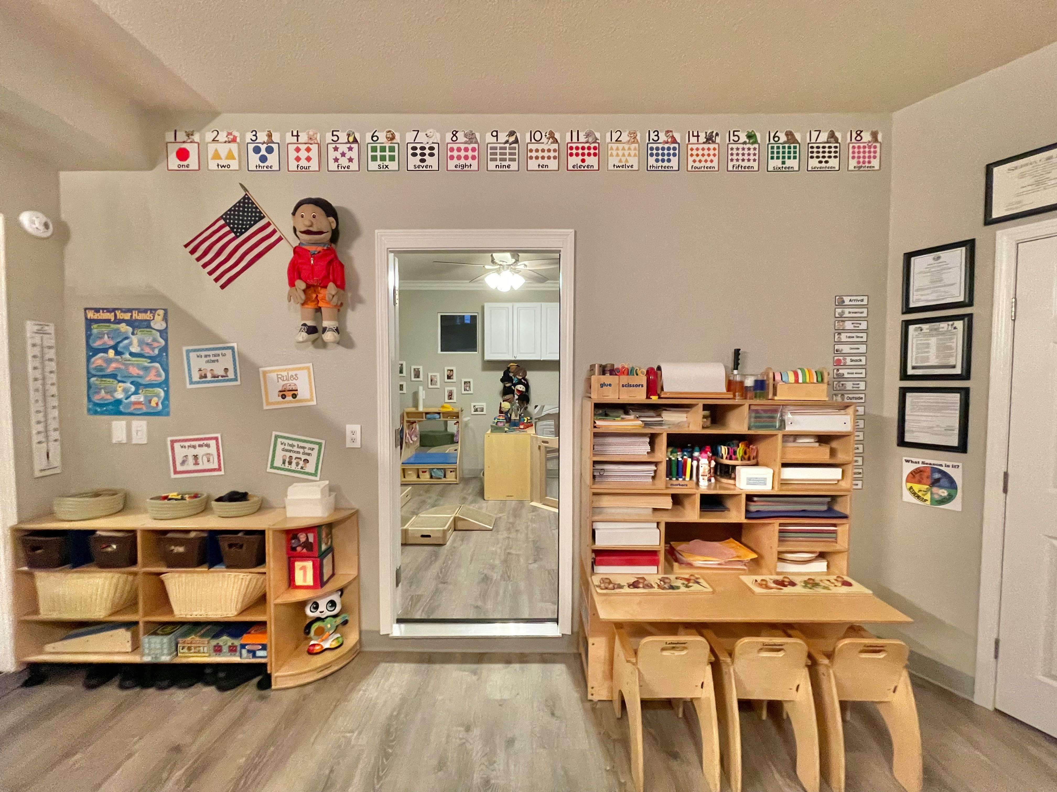 Classroom with shelves, tables, and chairs, American flag on wall