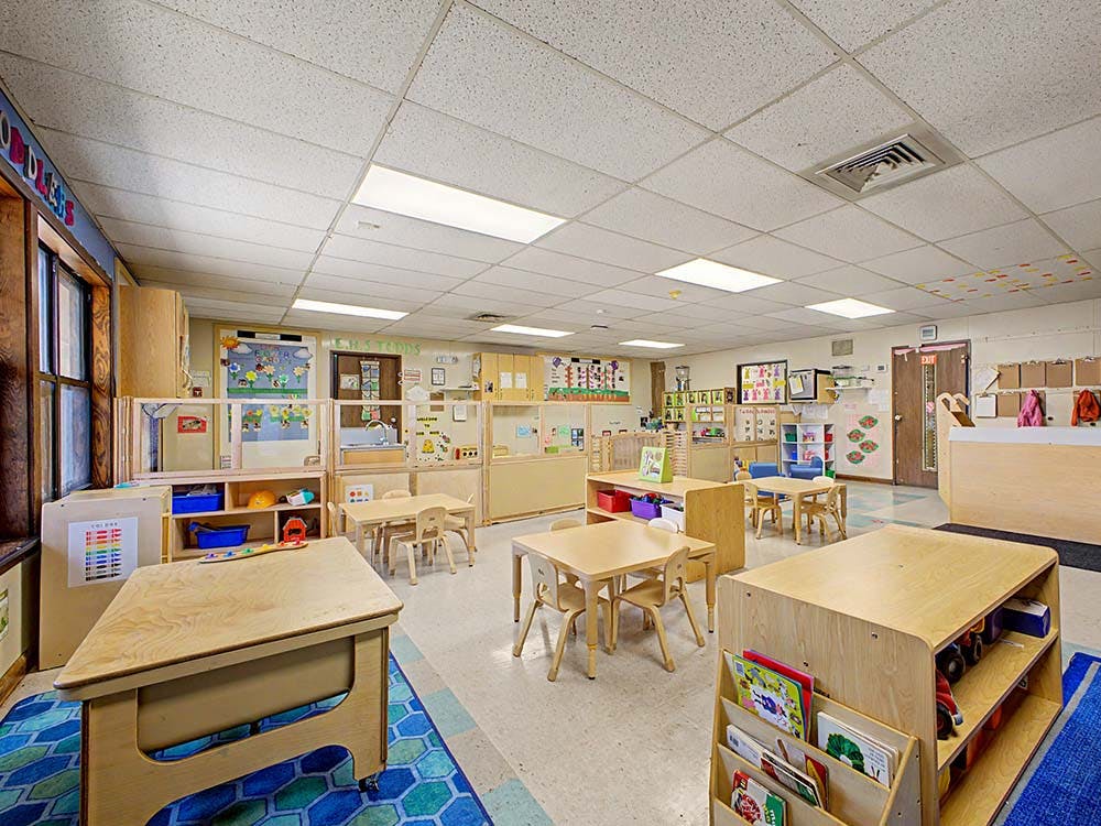 Empty children's classroom with small wooden tables and chairs