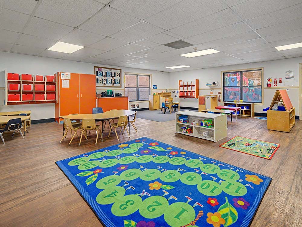 Empty children's classroom with small tables and chairs