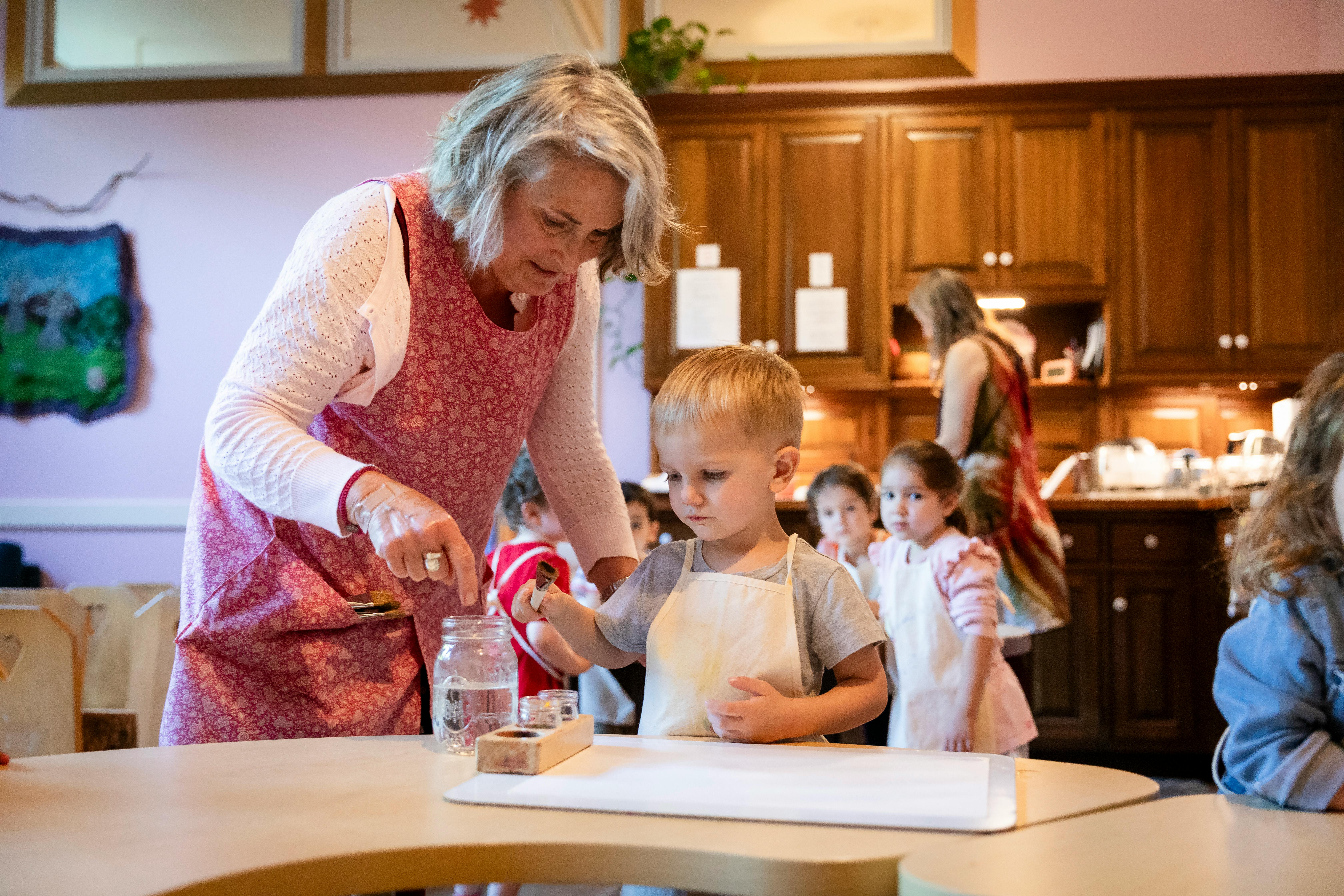 Adult and child in aprons working with a jar and tools at a table