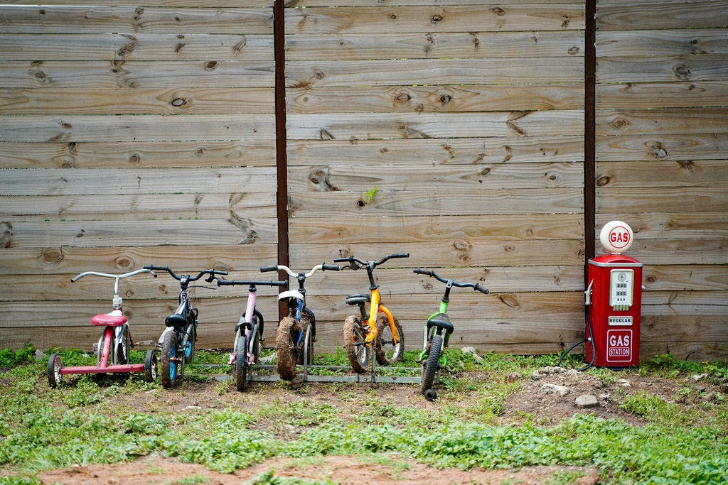 Several small bicycles and a tricycle parked by a toy gas pump