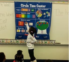 Child pointing at a "Circle Time Center" chart