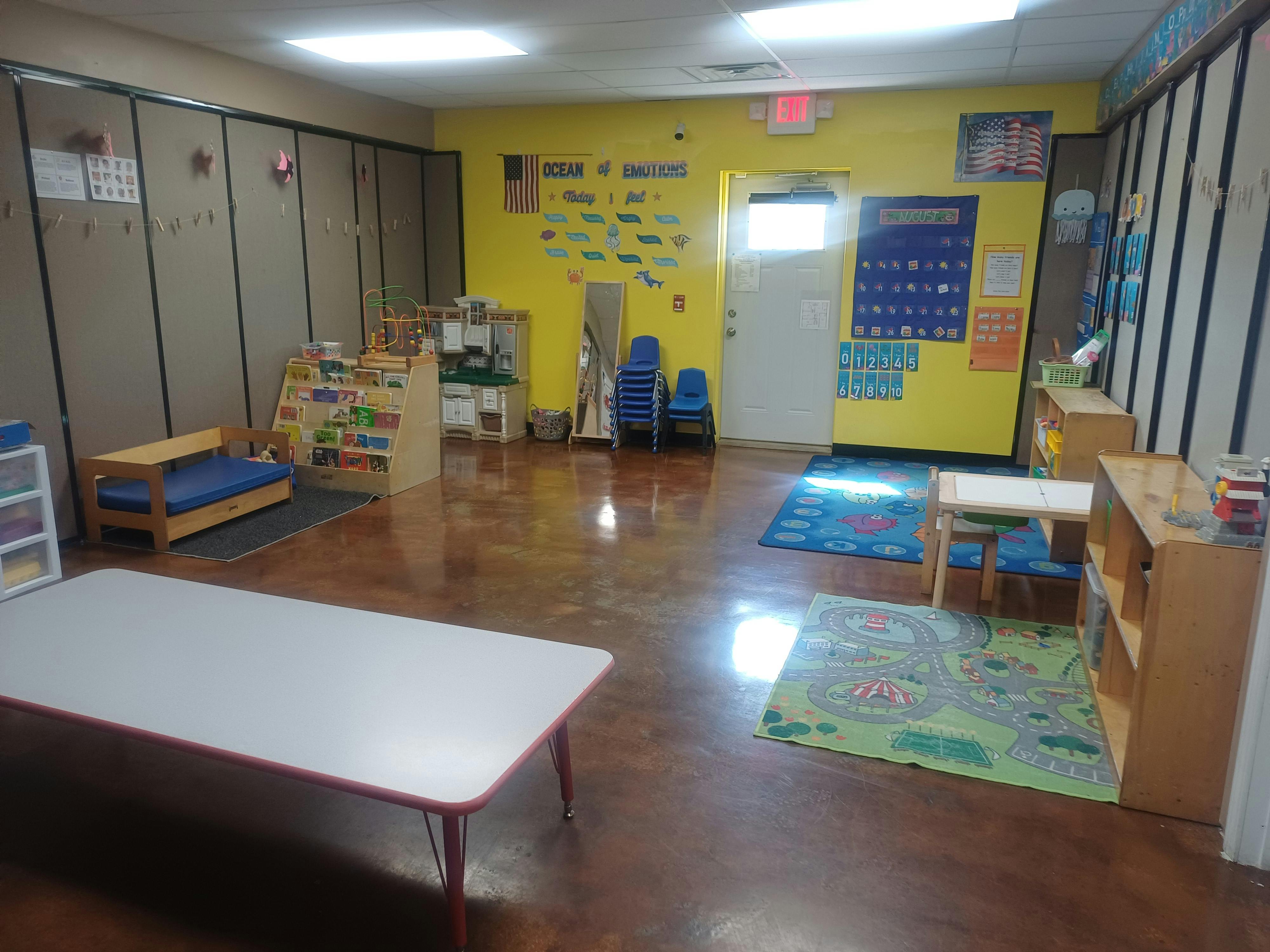 Empty classroom with yellow walls, tables, chairs, and rugs
