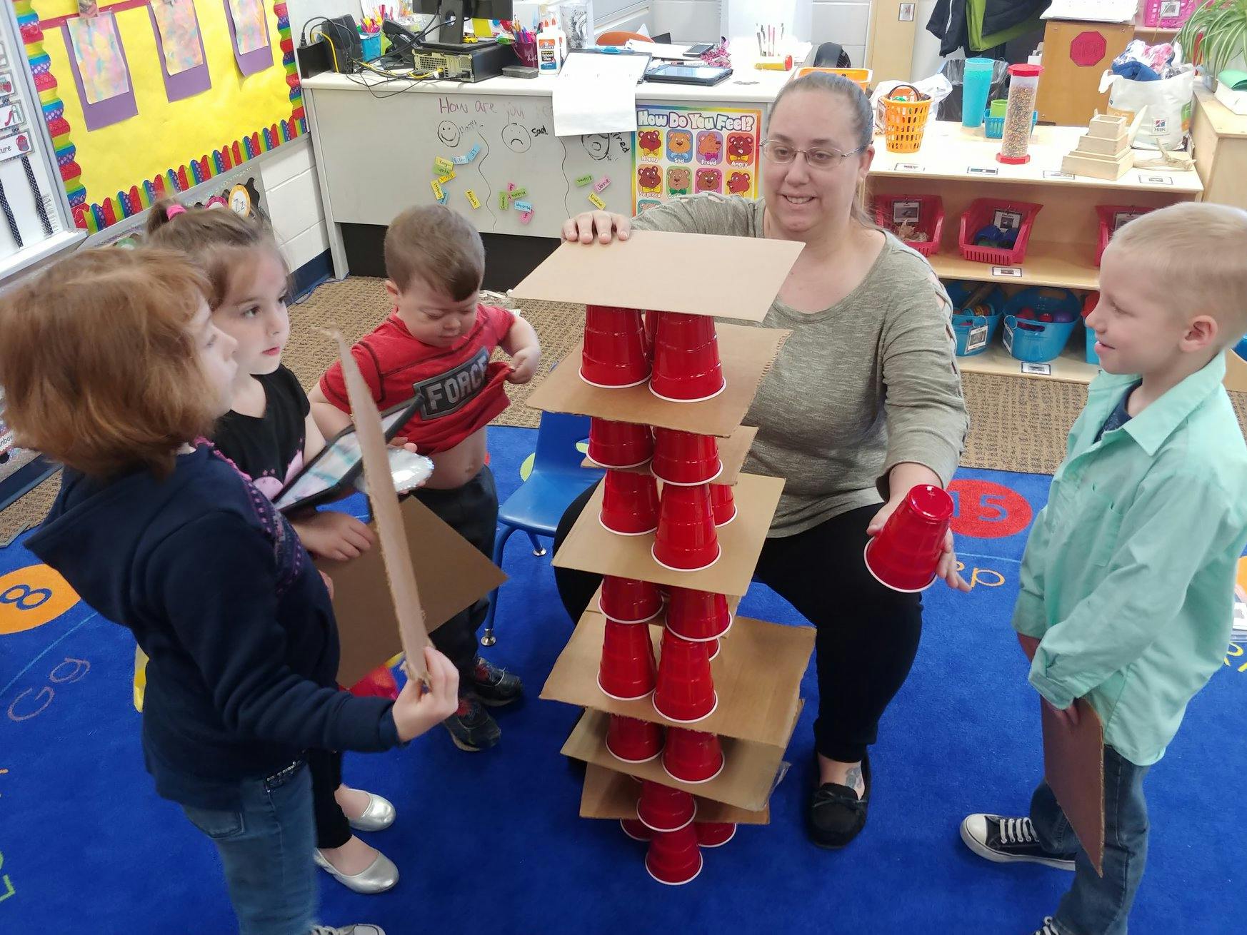 Adult and children building a tower with red cups and cardboard squares