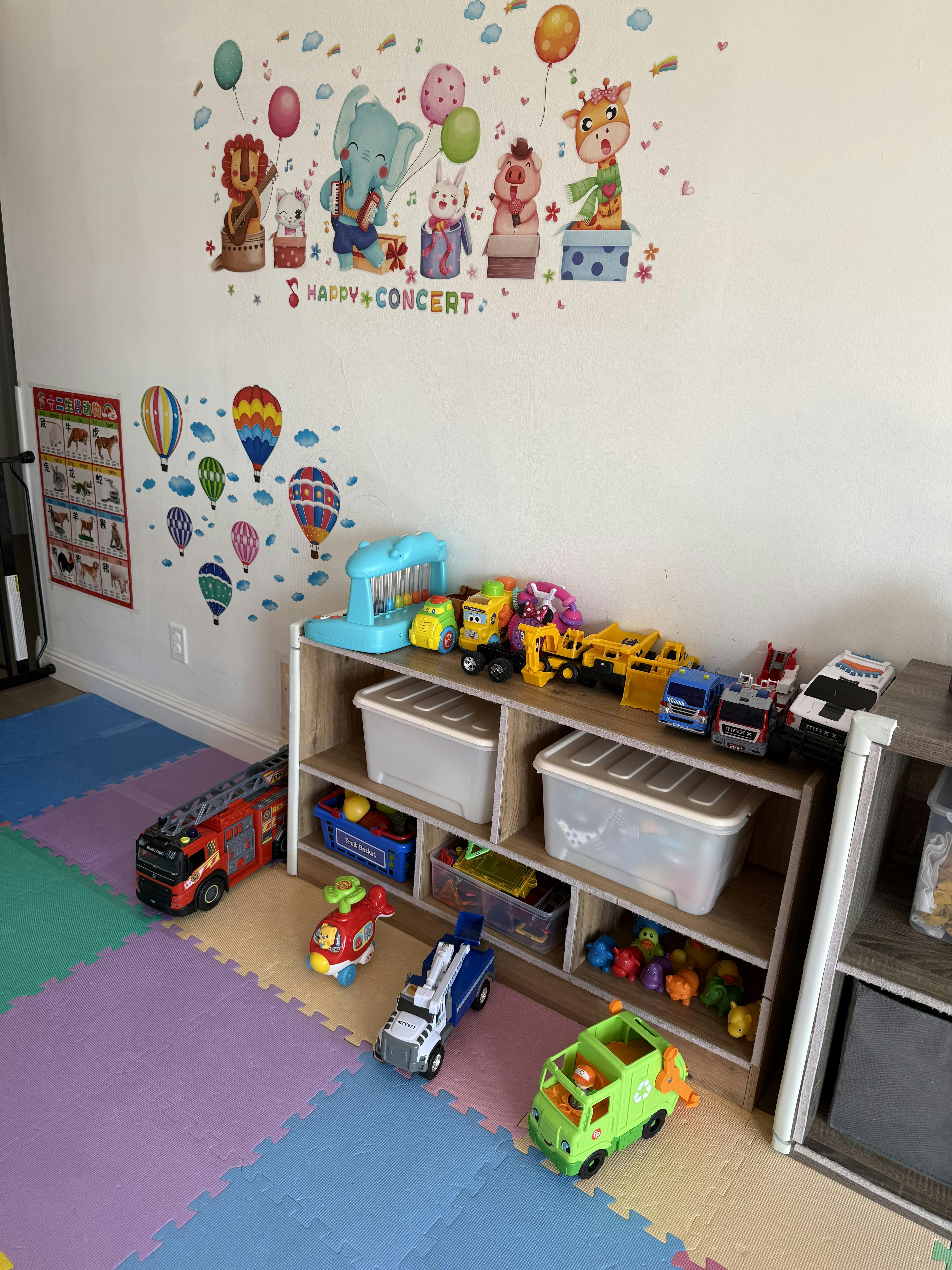 Playroom with wall decals, toy shelf, and colorful floor mats