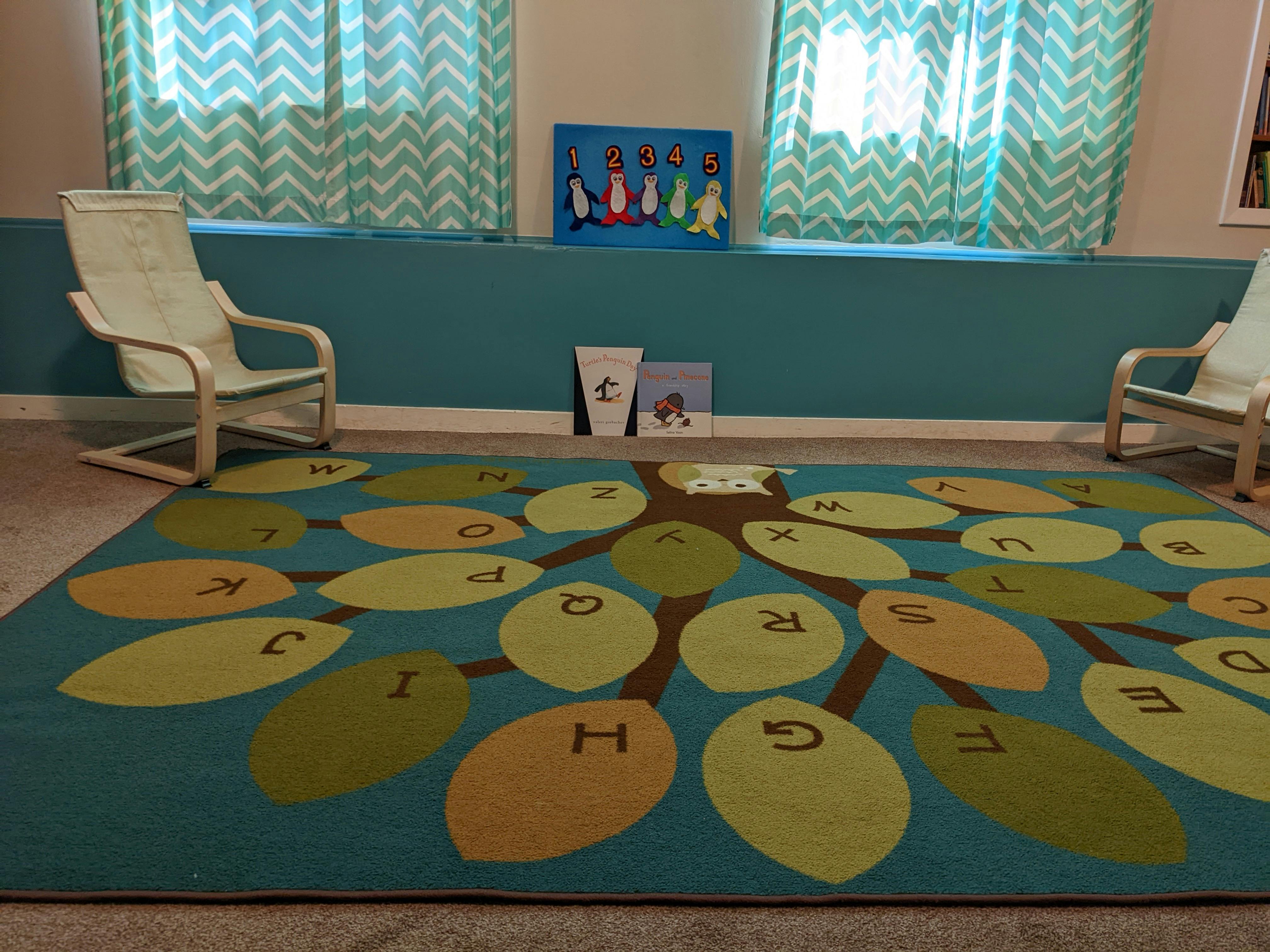 Alphabet rug in a room with two chairs and windows