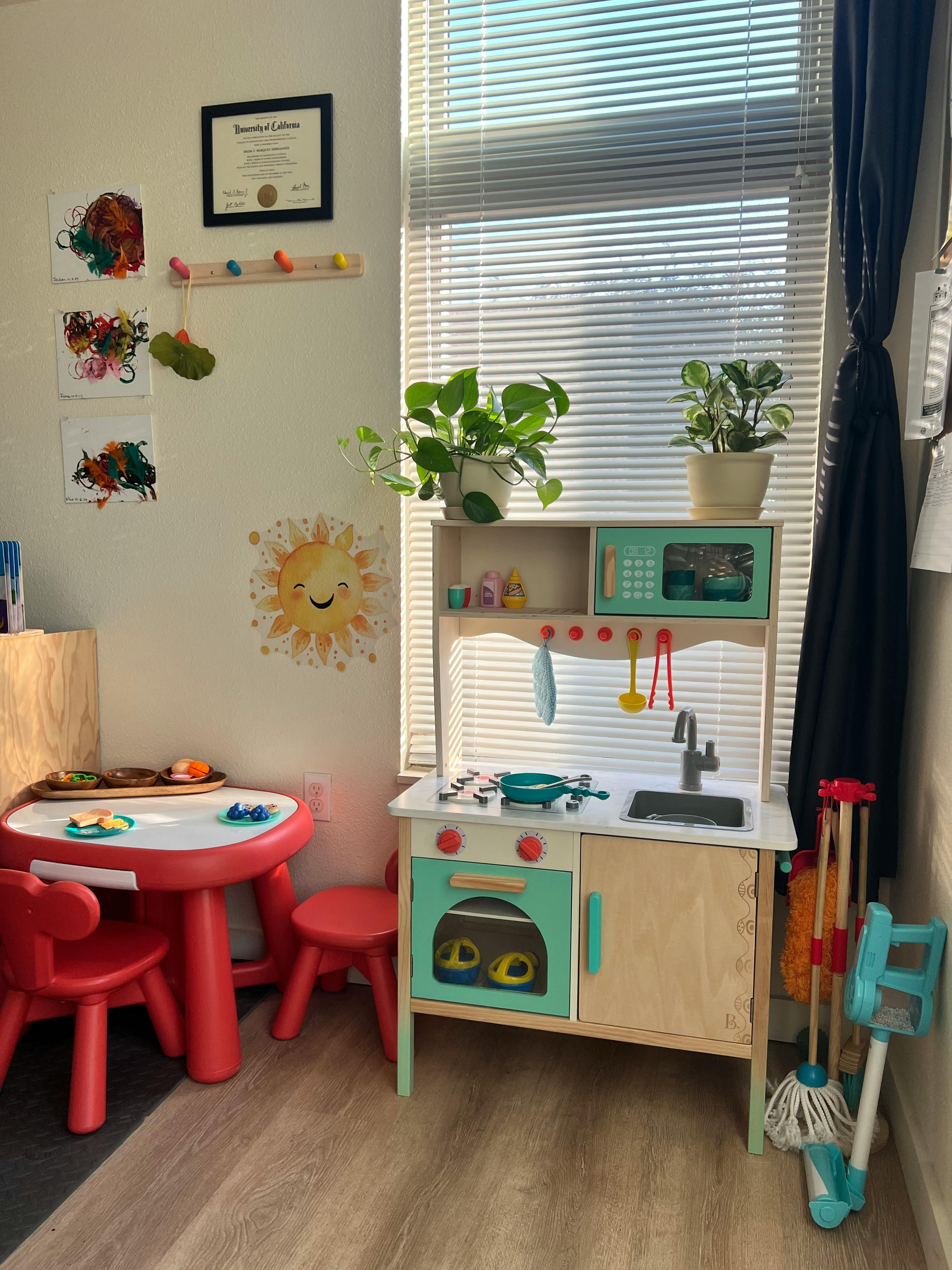 Child's play kitchen and red table with chairs in a room
