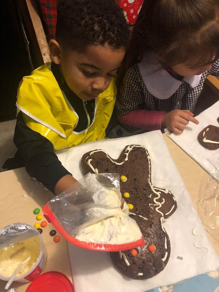Child decorating a gingerbread person with icing