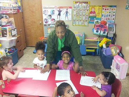 Adult and children at a red table with papers
