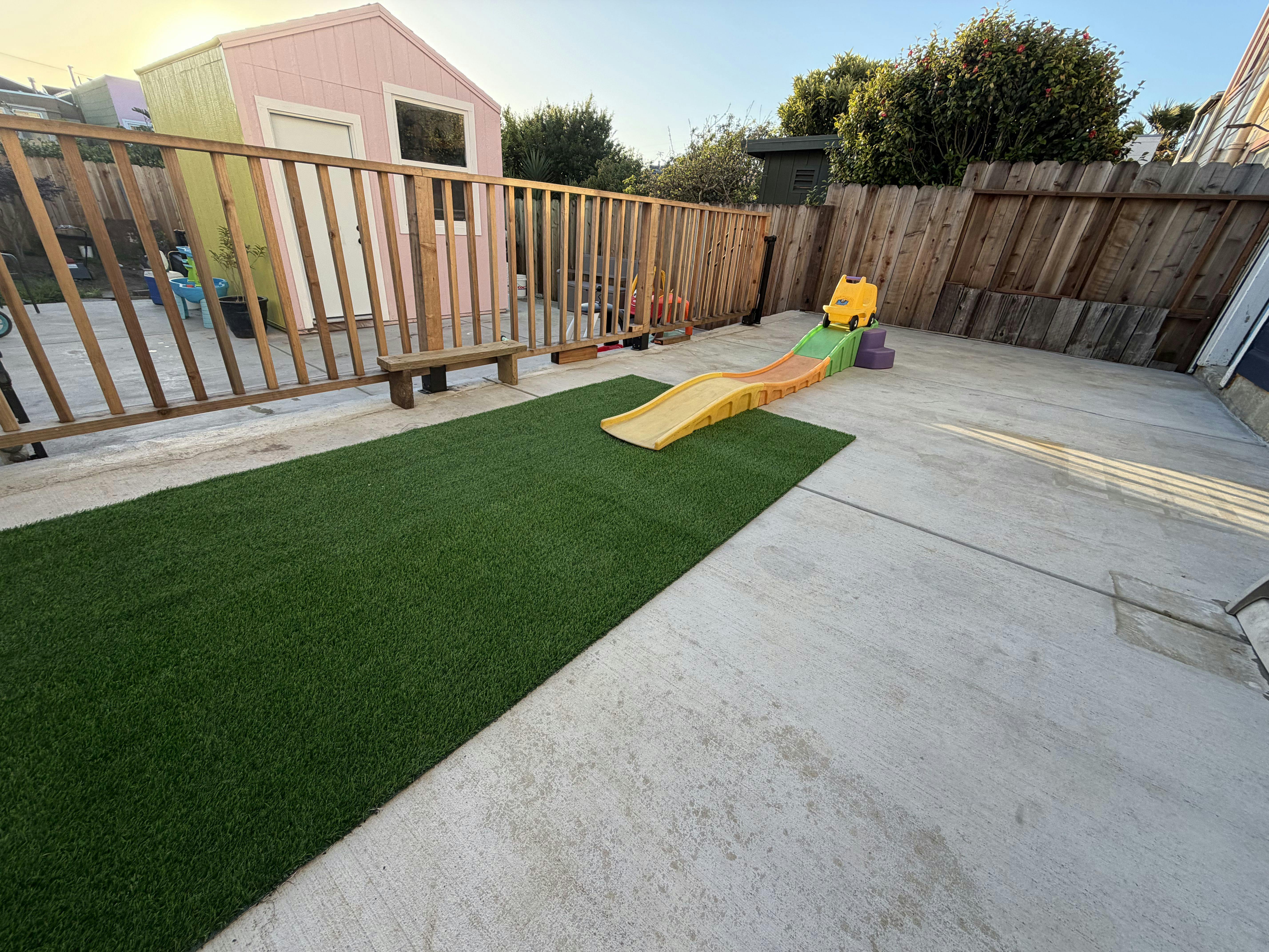 backyard with artificial turf, a children's slide, and a pink shed