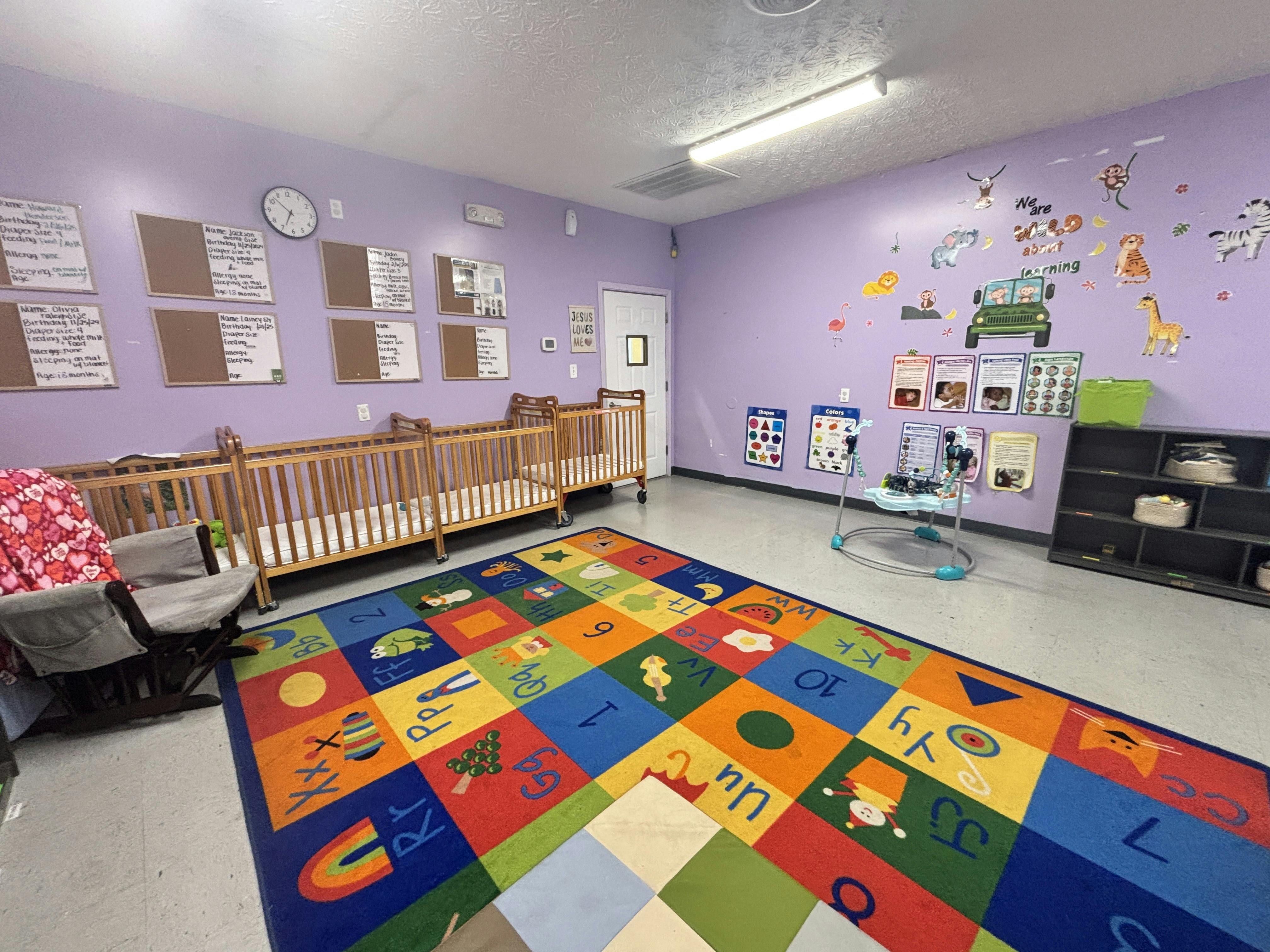 Colorful daycare classroom with cribs and alphabet rug