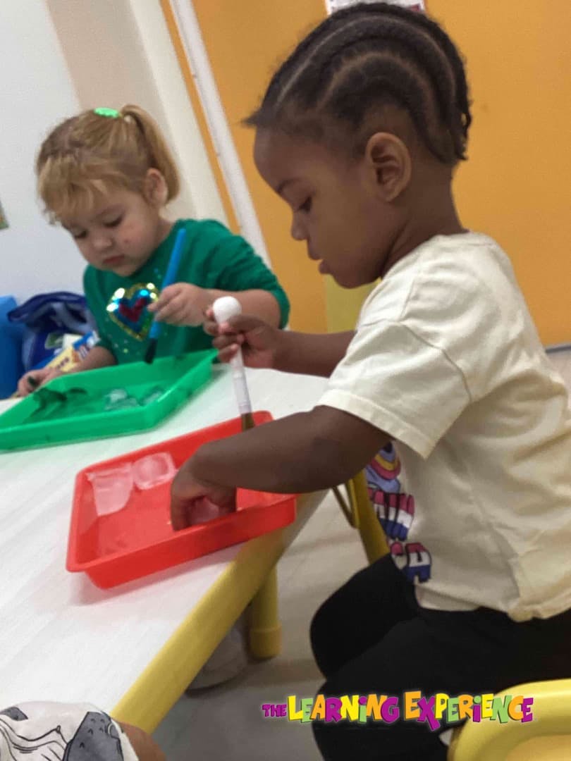 Two children playing with trays and small objects at a table