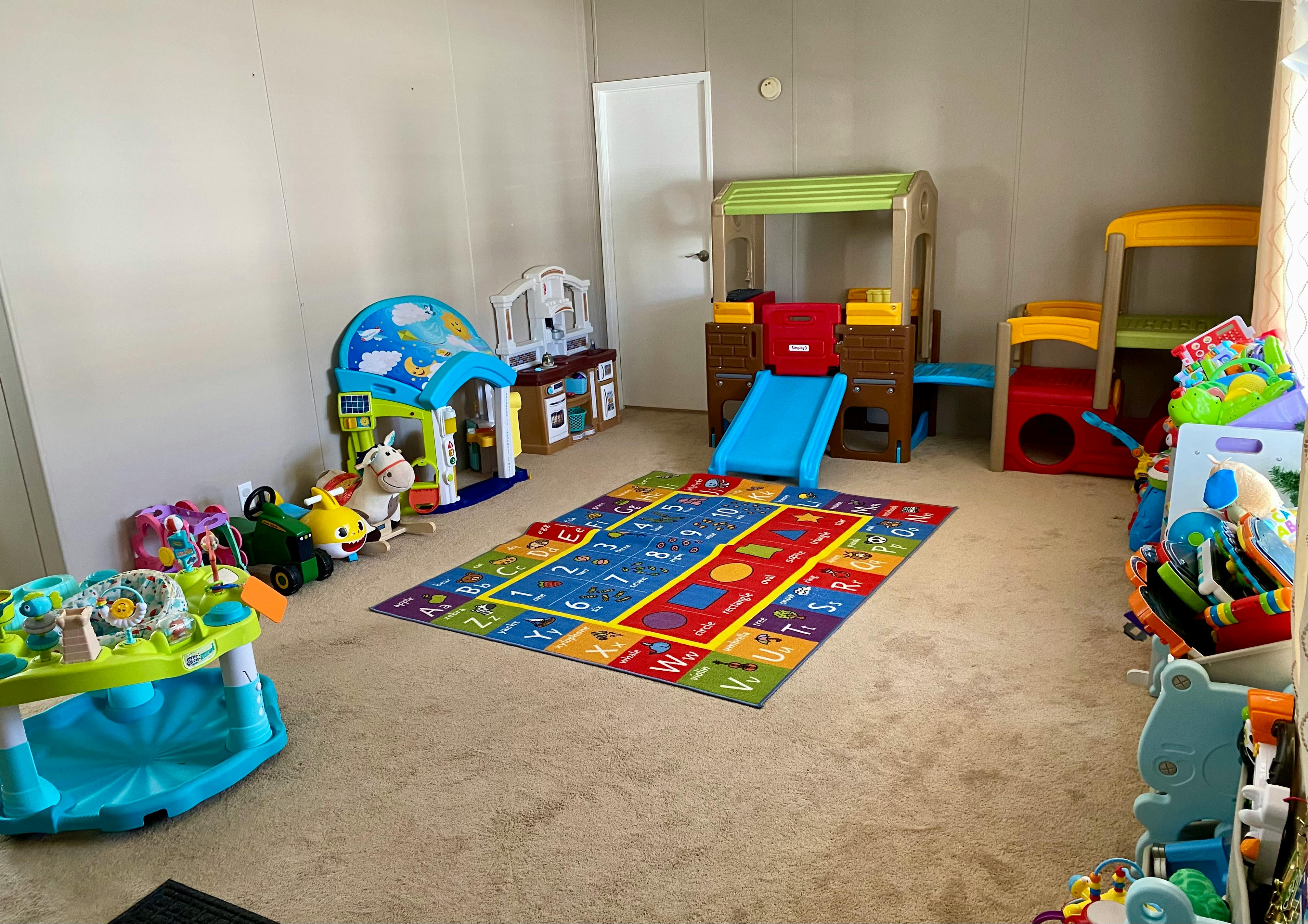 Playroom with a colorful rug, playhouses, and various toys