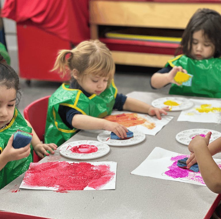 Children painting with sponges at a table