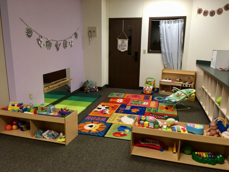 Playroom with colorful rugs, shelves of toys, and a small tunnel