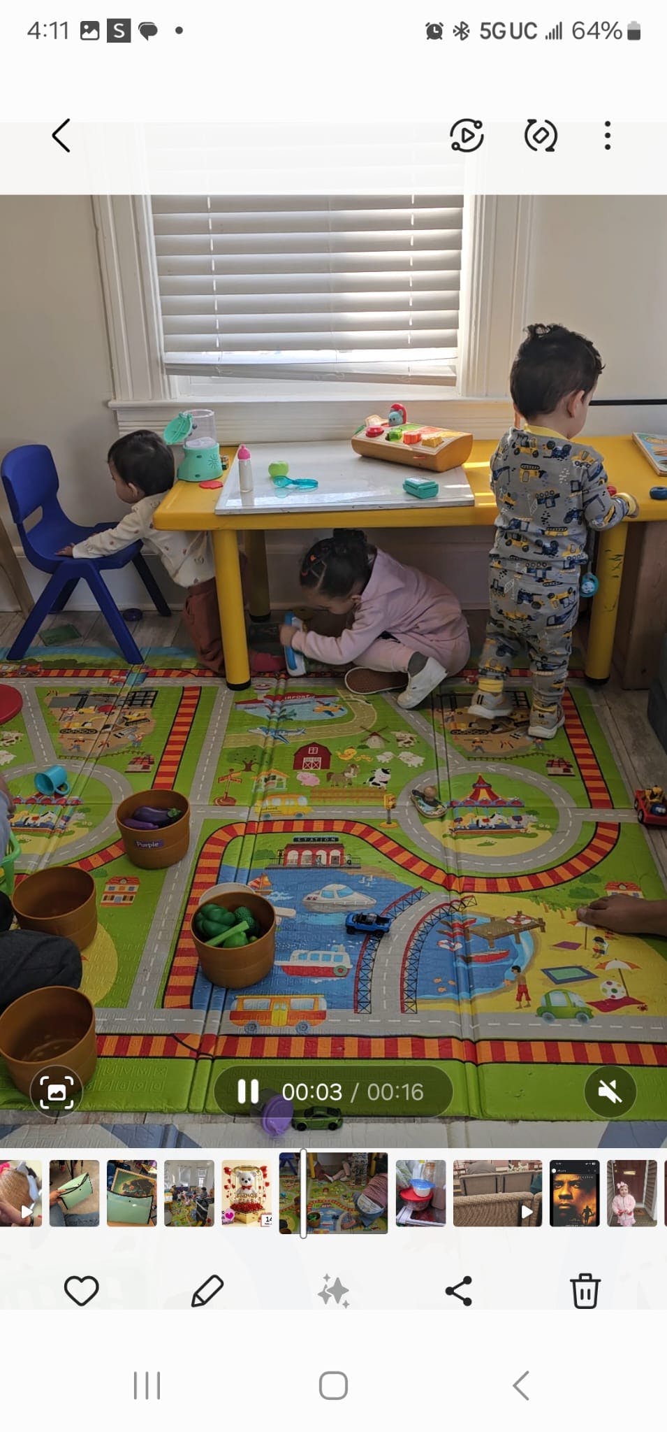 Three children playing with toys on a mat and at a small table