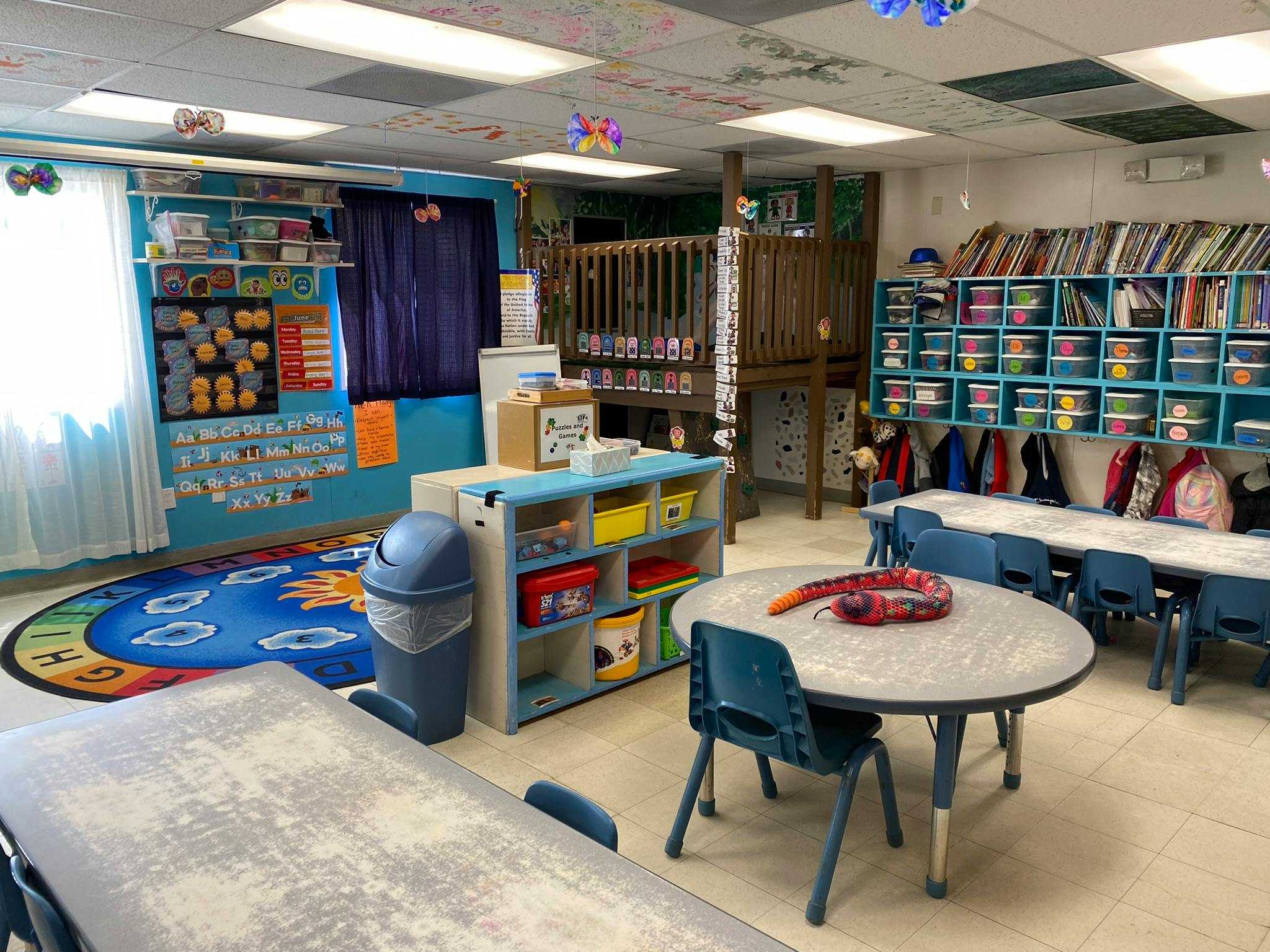 An empty early education classroom with small tables and chairs