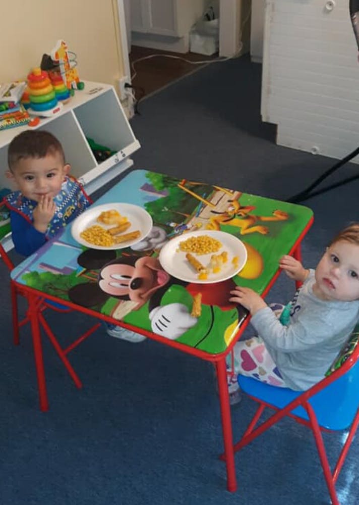 Two children sitting at a small table with plates of food