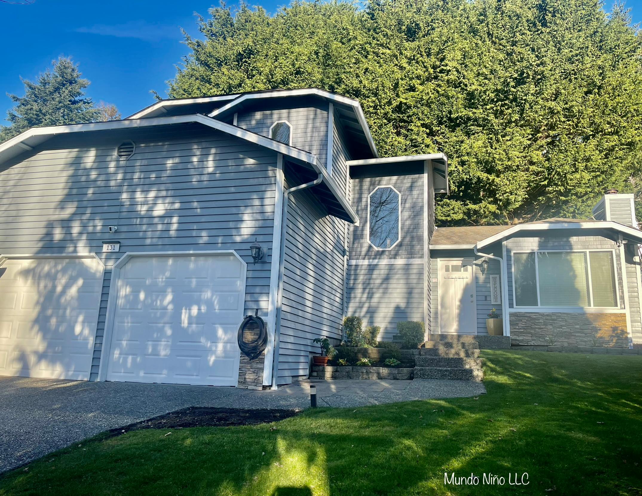 Exterior view of a house with a two-car garage and trees in the background