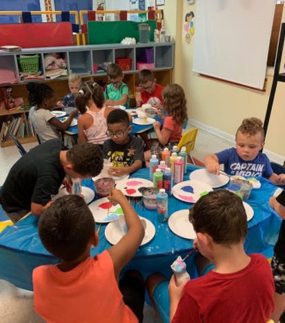 Children painting at a table in a classroom