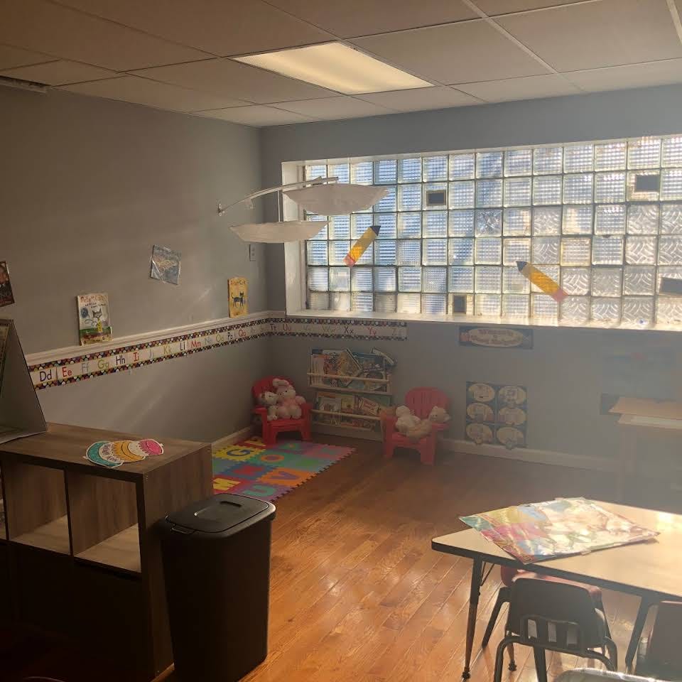 Empty classroom with colorful rug, small chairs, and glass block window