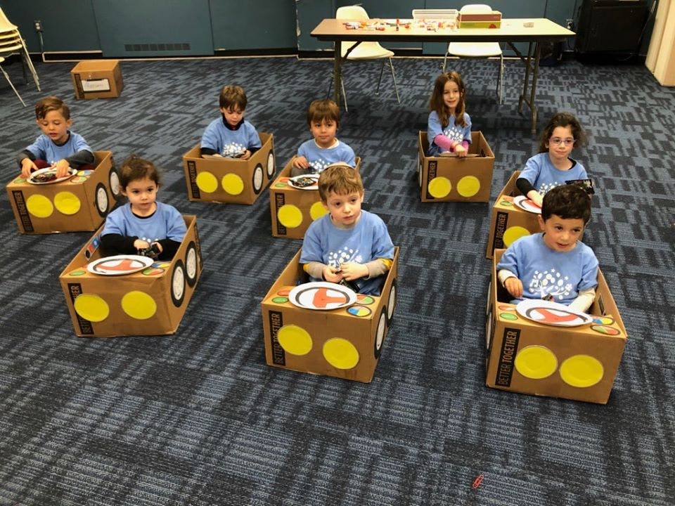 Children sitting in cardboard box cars