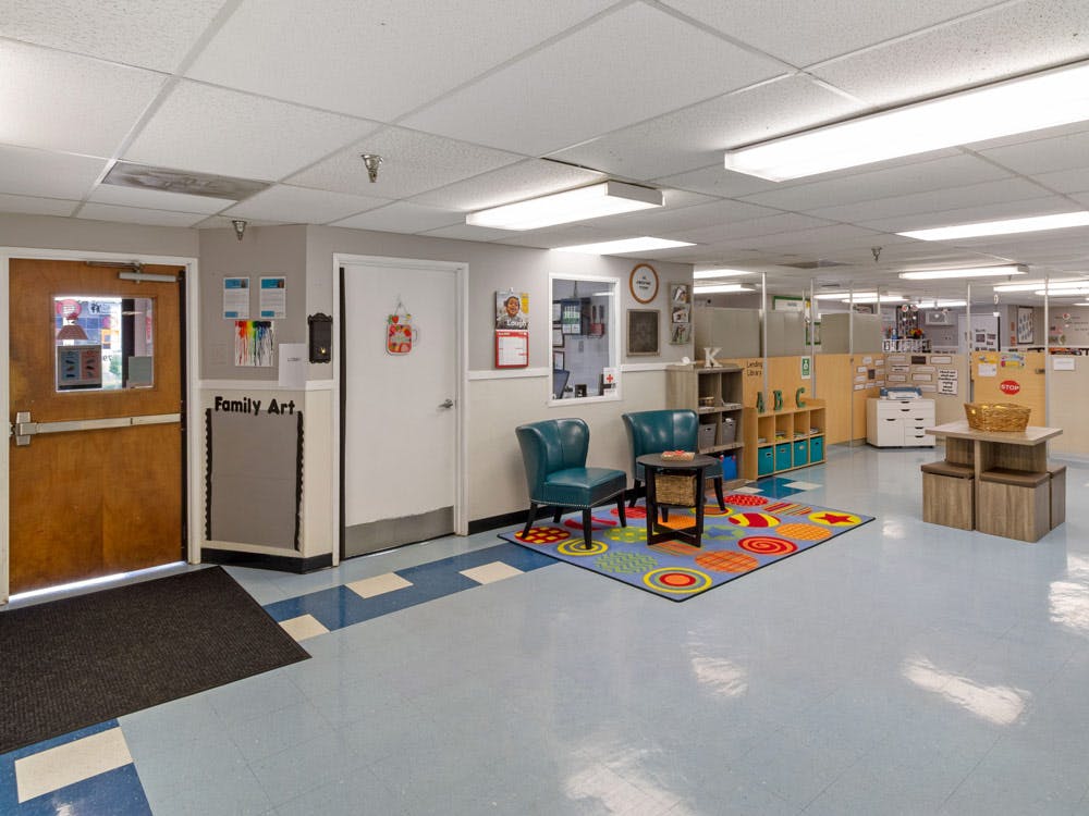 Entrance area of a preschool or daycare with blue chairs, colorful rug, and cubbies