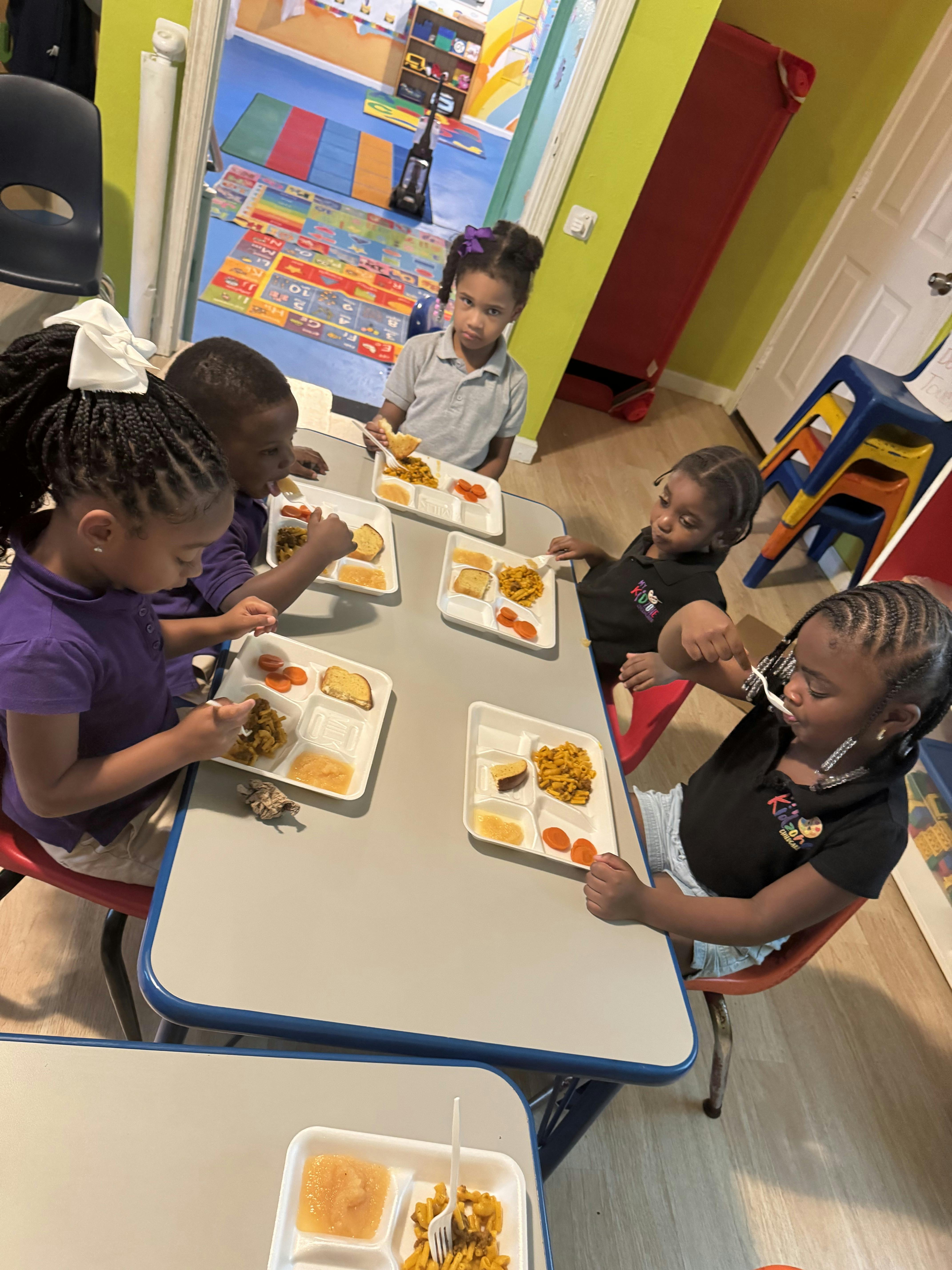 Children eating meals at a table in a classroom