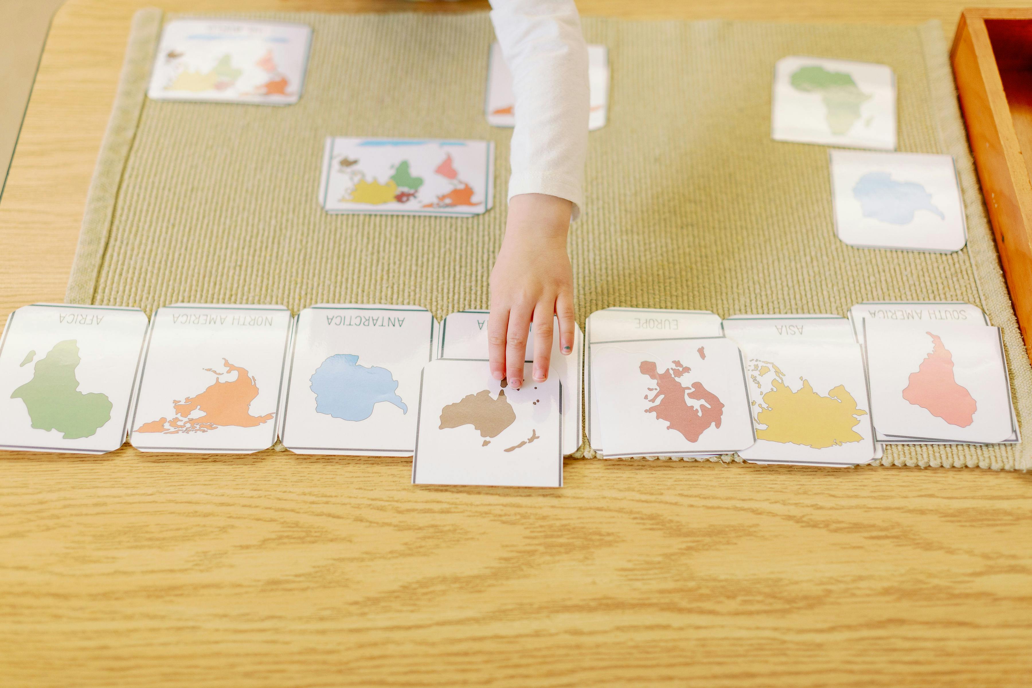 Child's hand placing a continent puzzle piece on a mat