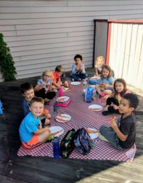 Group of children sitting on a blanket eating outdoors
