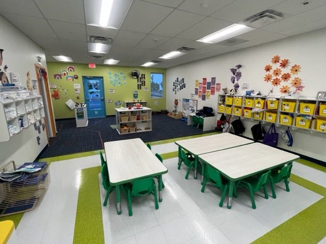 Classroom with small tables and chairs, decorated walls, and storage shelves