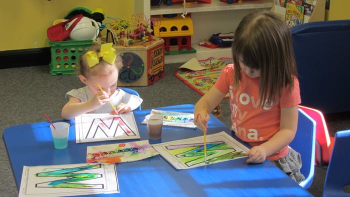 Two children painting and coloring at a table