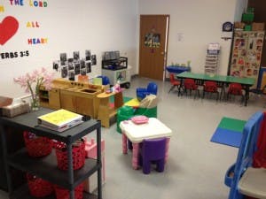 Playroom with small tables and chairs, toy kitchen, and wall decorations