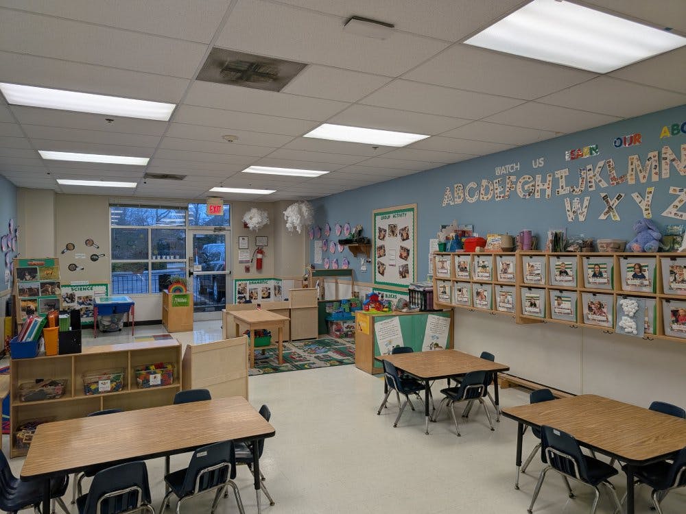Classroom with small tables and chairs, alphabet on the wall, and cubbies