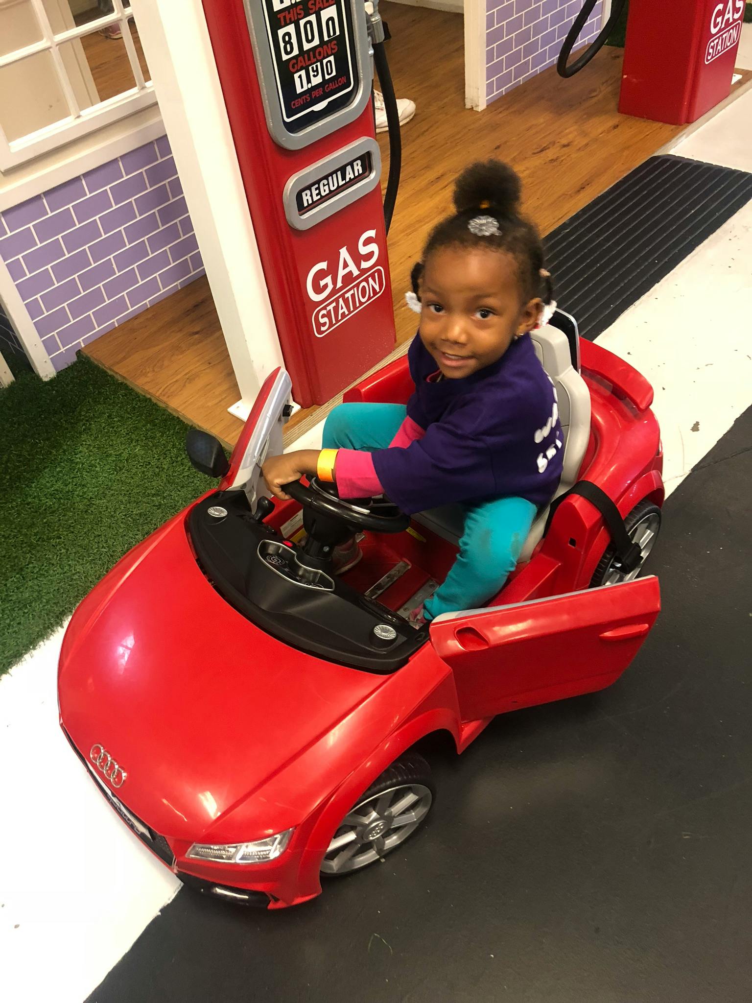 Child in a toy car at a play gas station