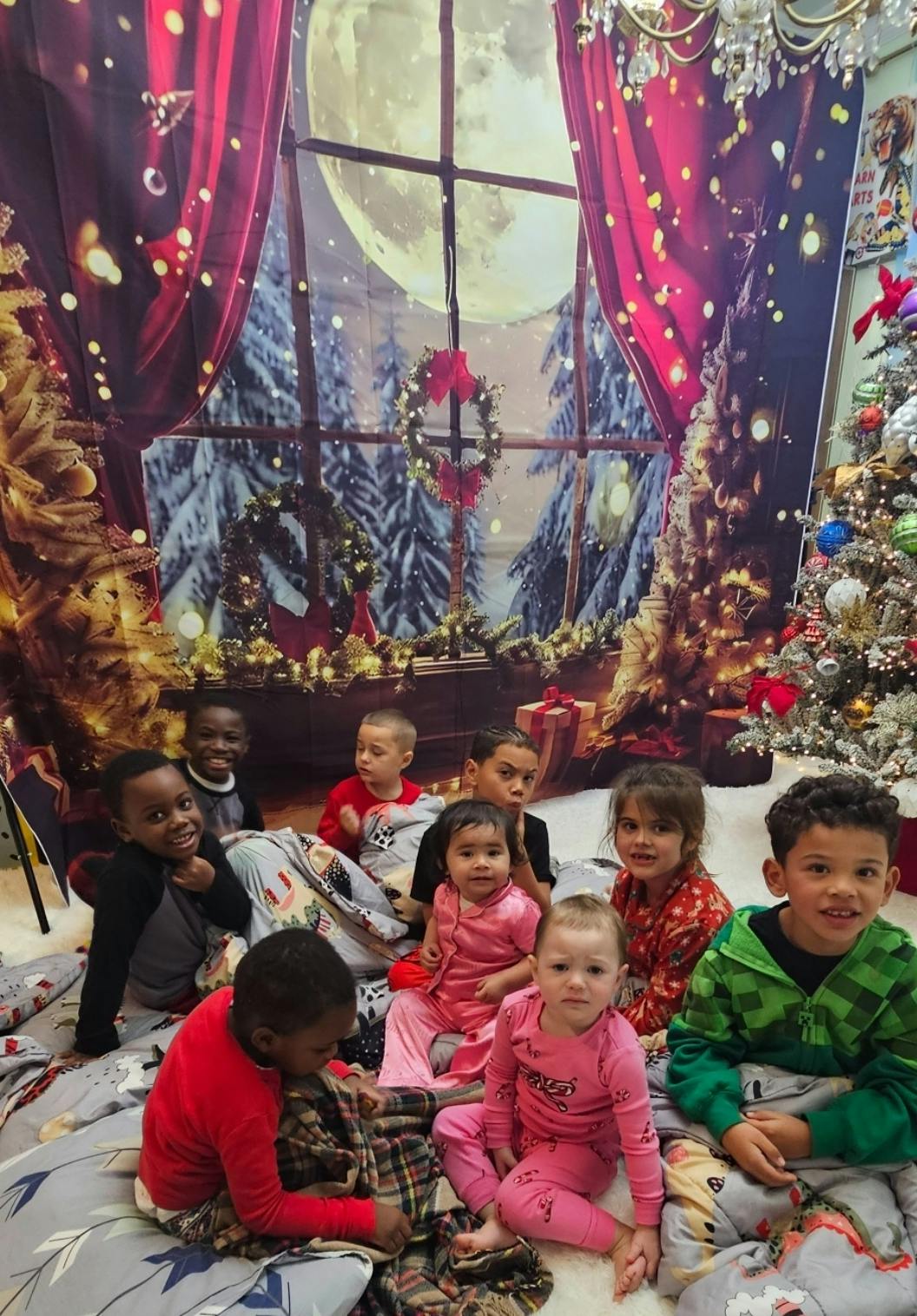 Group of children sitting together in front of a holiday-themed backdrop