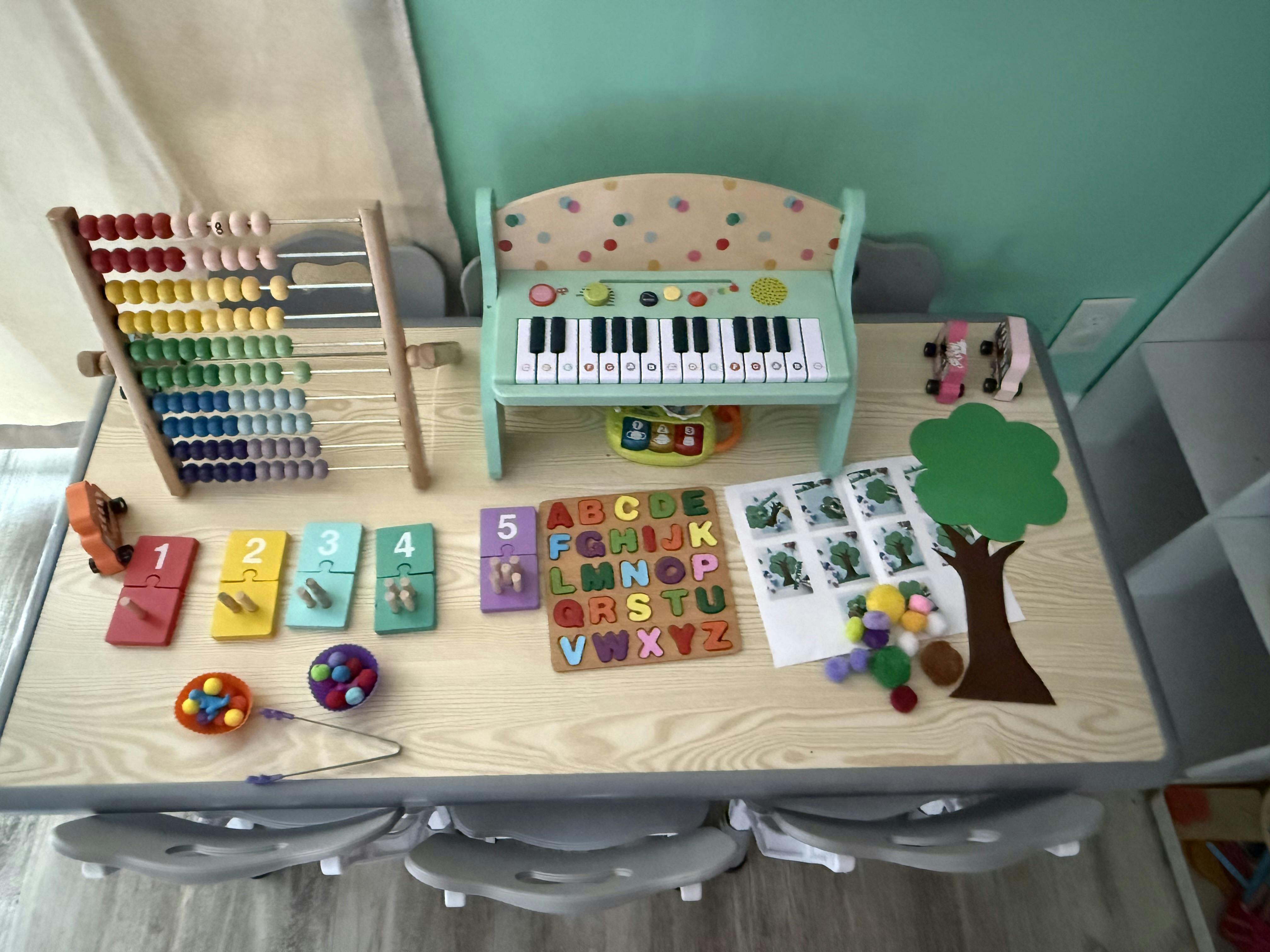 Educational toys including an abacus, toy piano, and alphabet puzzle on a table