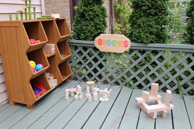 Wooden storage unit with toys and wooden blocks on a deck, sign says BLOCKS