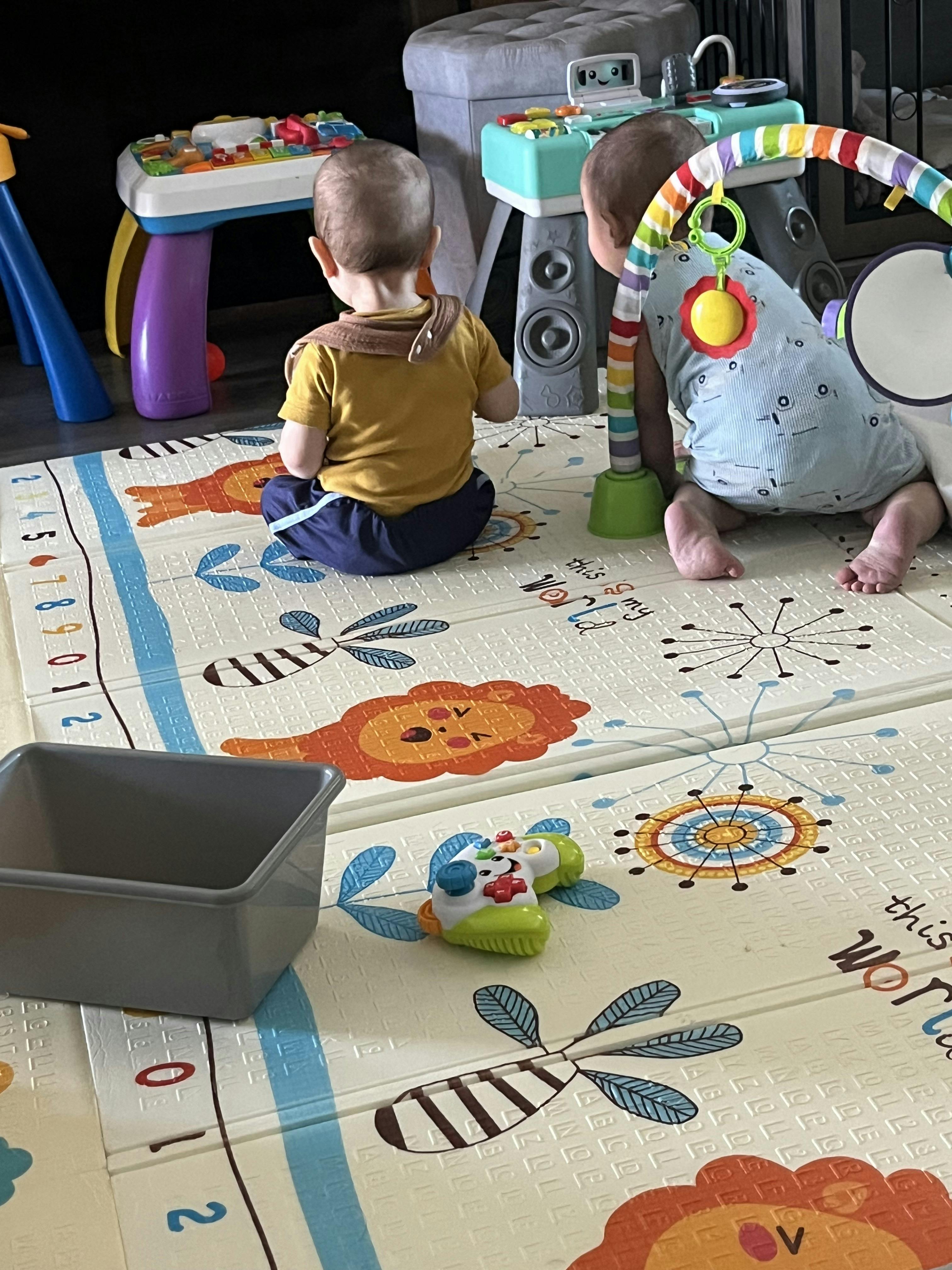 Two children playing on a mat with toys