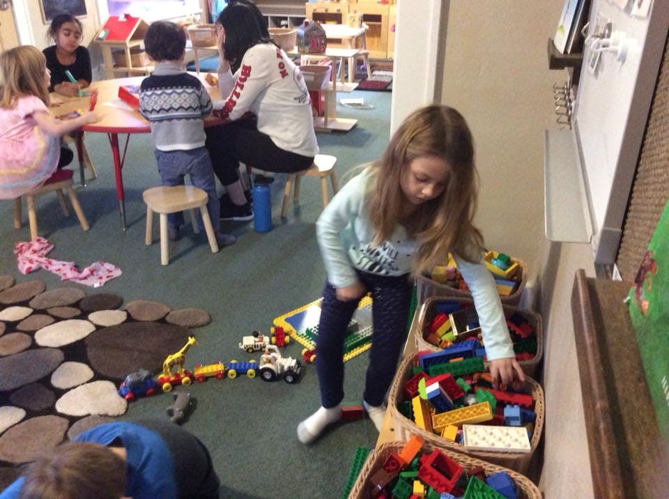 Child reaching into a bin of toys in a classroom