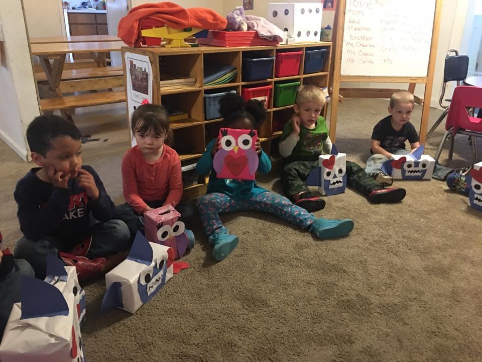 Four children sitting on a carpeted floor with craft boxes